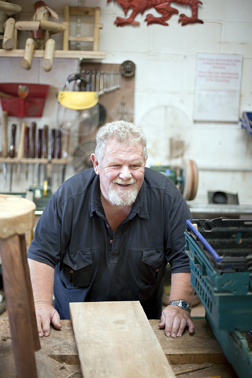 A man in a wood workshop smiling