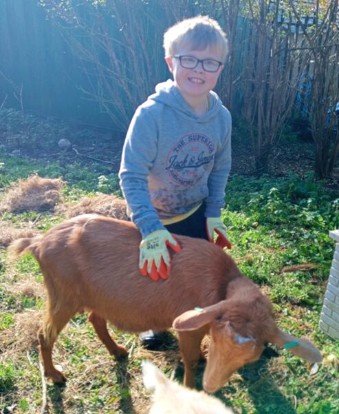 A young person standing next to a goat.