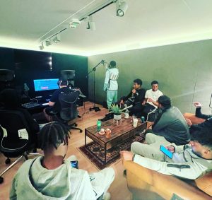 A group of young people from LAB7 recording music in a studio.